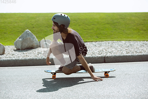 Image of Skateboarder doing a trick at the city\'s street in sunny day