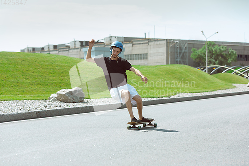 Image of Skateboarder doing a trick at the city\'s street in sunny day