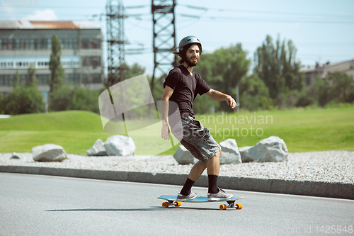 Image of Skateboarder doing a trick at the city\'s street in sunny day