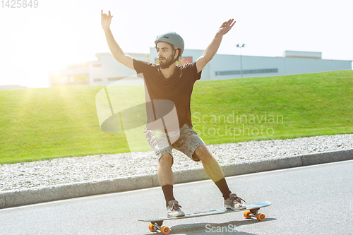 Image of Skateboarder doing a trick at the city\'s street in sunny day