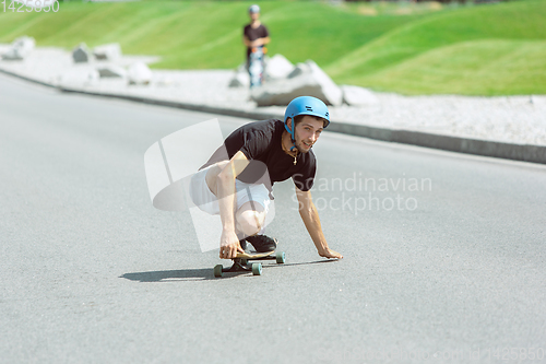 Image of Skateboarder doing a trick at the city\'s street in sunny day