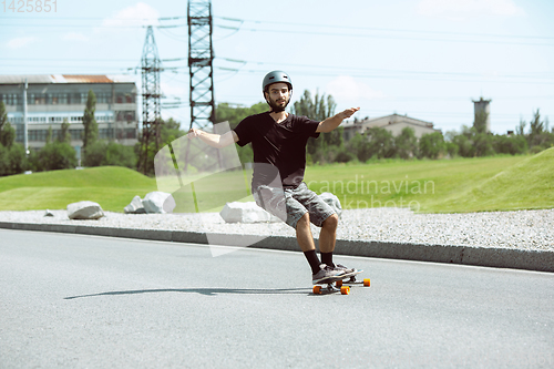 Image of Skateboarder doing a trick at the city\'s street in sunny day