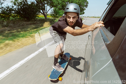 Image of Skateboarder doing a trick at the city\'s street in sunny day