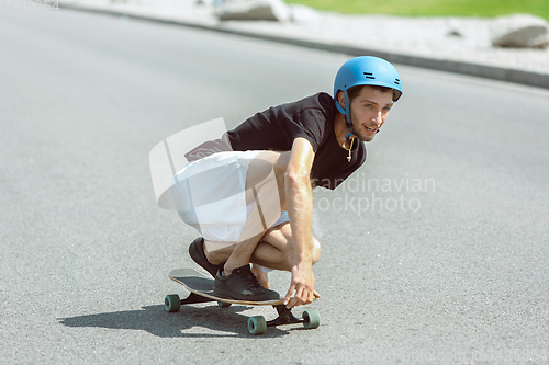 Image of Skateboarder doing a trick at the city\'s street in sunny day