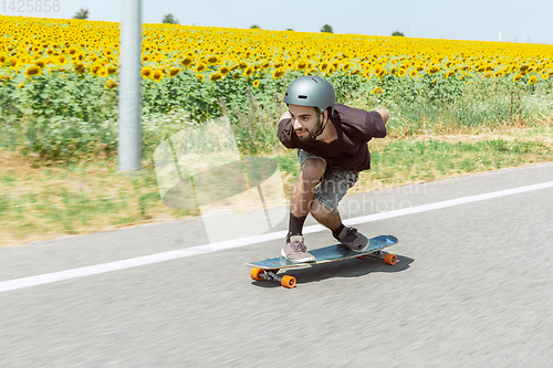 Image of Skateboarder doing a trick at the city\'s street in sunny day