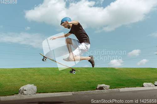 Image of Skateboarder doing a trick at the city\'s street in sunny day