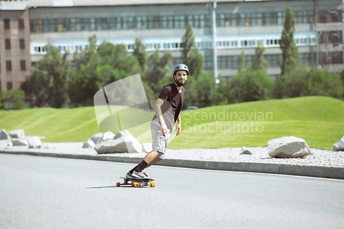 Image of Skateboarder doing a trick at the city\'s street in sunny day