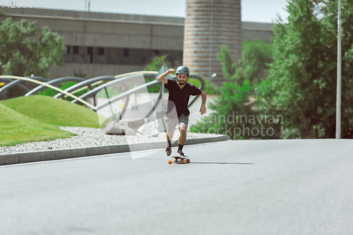 Image of Skateboarder doing a trick at the city\'s street in sunny day