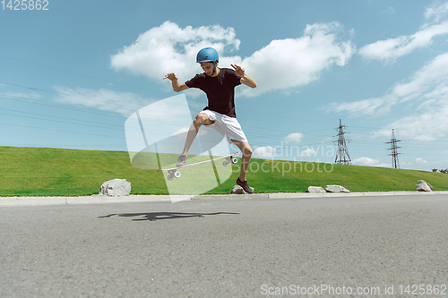 Image of Skateboarder doing a trick at the city\'s street in sunny day