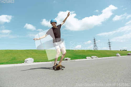 Image of Skateboarder doing a trick at the city\'s street in sunny day