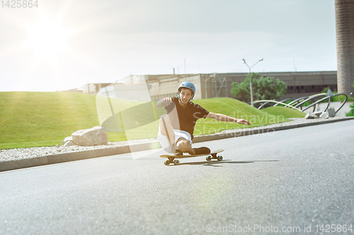 Image of Skateboarder doing a trick at the city\'s street in sunny day