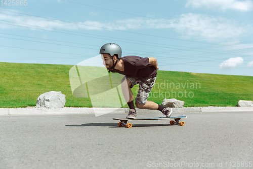 Image of Skateboarder doing a trick at the city\'s street in sunny day