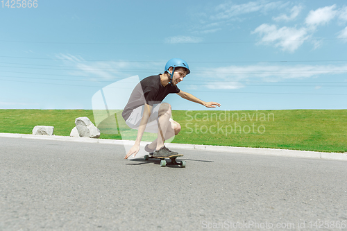 Image of Skateboarder doing a trick at the city\'s street in sunny day