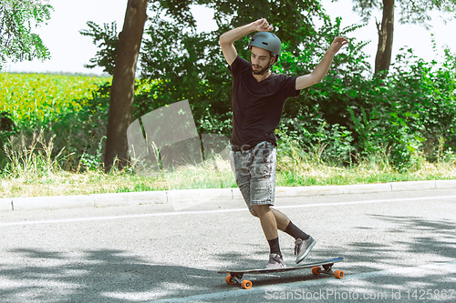 Image of Skateboarder doing a trick at the city\'s street in sunny day