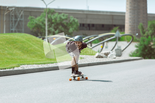 Image of Skateboarder doing a trick at the city\'s street in sunny day