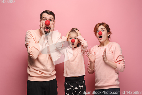 Image of Portrait of young family celebrating red nose day on coral background
