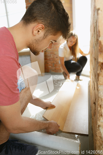 Image of Young couple doing apartment repair together themselves