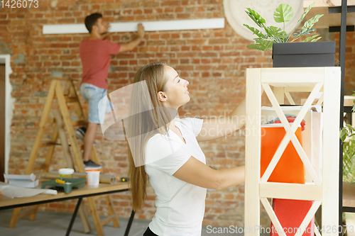 Image of Young couple doing apartment repair together themselves