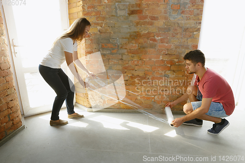 Image of Young couple doing apartment repair together themselves