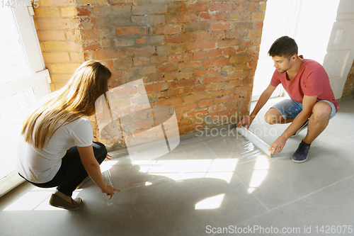 Image of Young couple doing apartment repair together themselves