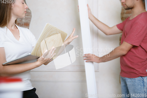 Image of Young couple doing apartment repair together themselves