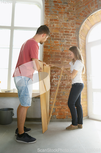 Image of Young couple doing apartment repair together themselves