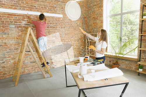 Image of Young couple doing apartment repair together themselves