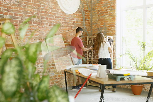 Image of Young couple doing apartment repair together themselves