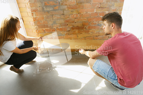 Image of Young couple doing apartment repair together themselves