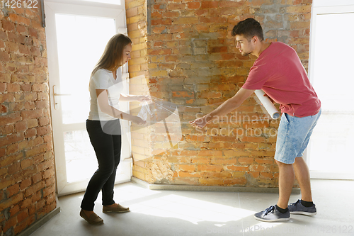 Image of Young couple doing apartment repair together themselves