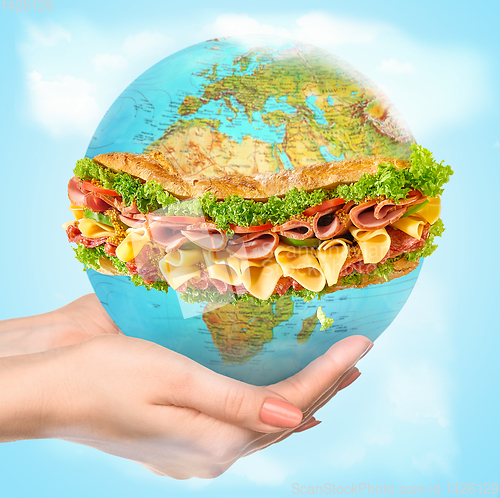 Image of Save healthy food - female hands holding a globe as a sandwich