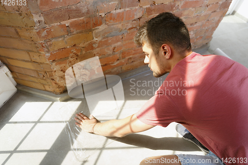 Image of Young man doing apartment repair hisselfes