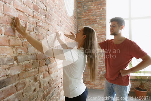 Image of Young couple doing apartment repair together themselves