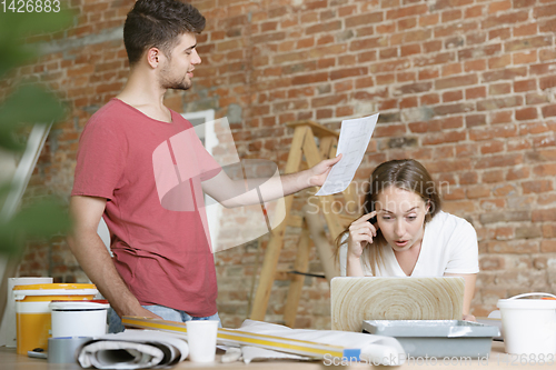 Image of Young couple doing apartment repair together themselves