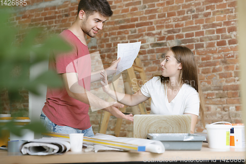 Image of Young couple doing apartment repair together themselves