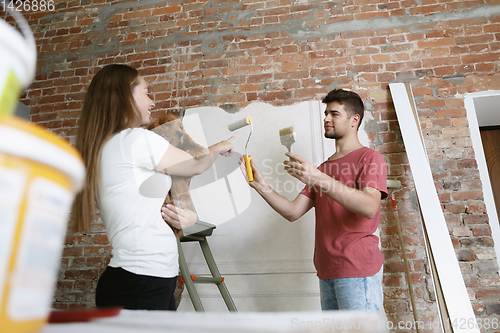 Image of Young couple doing apartment repair together themselves