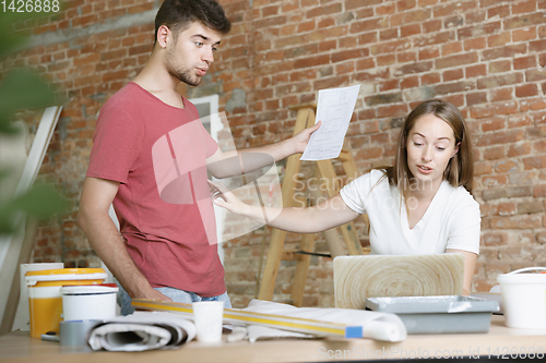 Image of Young couple doing apartment repair together themselves