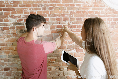 Image of Young couple doing apartment repair together themselves