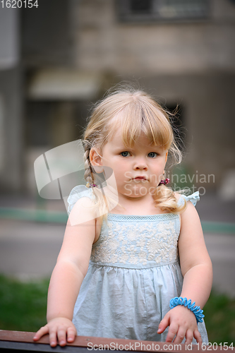 Image of Little girl in an urban setting smiles at the camera.