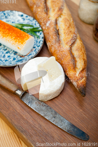 Image of French cheese and fresh  baguette on a wood cutter