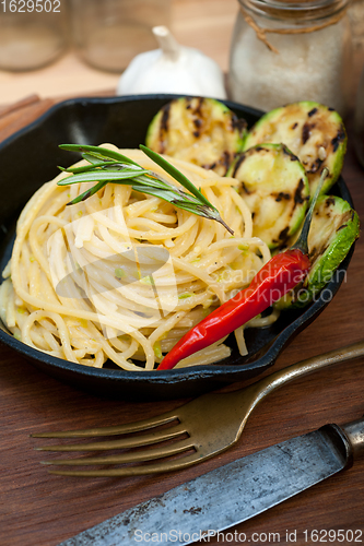 Image of italian spaghetti pasta with zucchini sauce on iron skillet