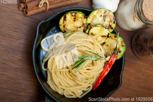 Image of italian spaghetti pasta with zucchini sauce on iron skillet