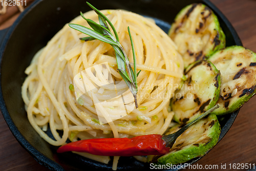 Image of italian spaghetti pasta with zucchini sauce on iron skillet
