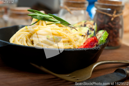 Image of italian spaghetti pasta with zucchini sauce on iron skillet