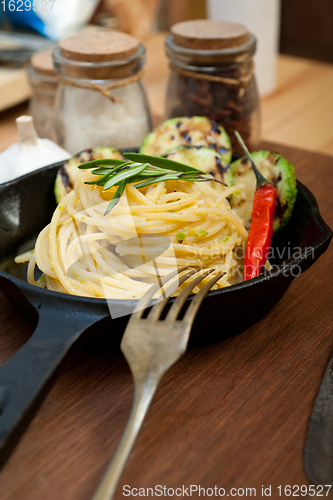 Image of italian spaghetti pasta with zucchini sauce on iron skillet
