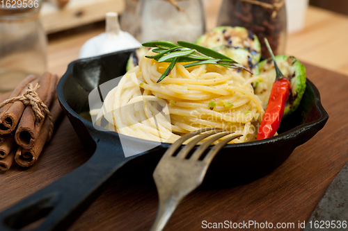 Image of italian spaghetti pasta with zucchini sauce on iron skillet