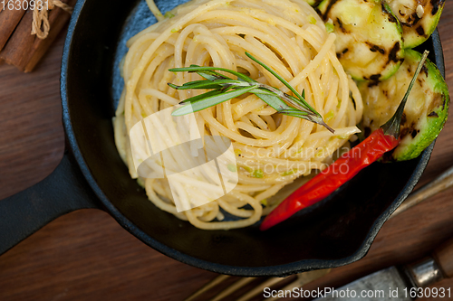 Image of italian spaghetti pasta with zucchini sauce on iron skillet