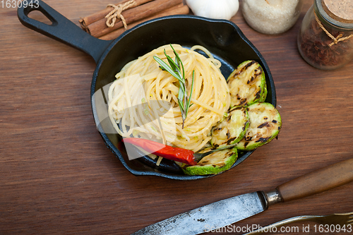 Image of italian spaghetti pasta with zucchini sauce on iron skillet