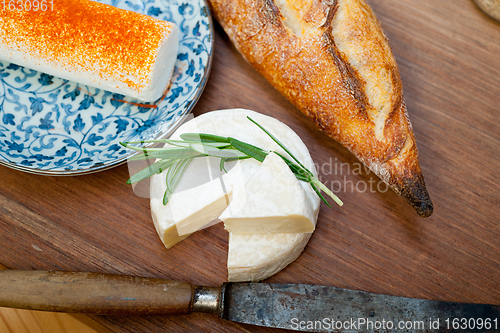 Image of French cheese and fresh  baguette on a wood cutter