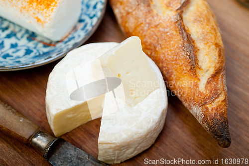 Image of French cheese and fresh  baguette on a wood cutter